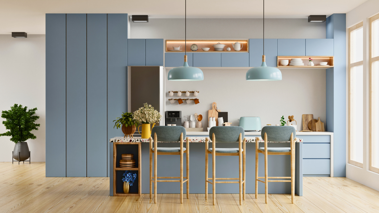 Bright modern kitchen with blue cabinetry, pendant lights, and three bar stools.